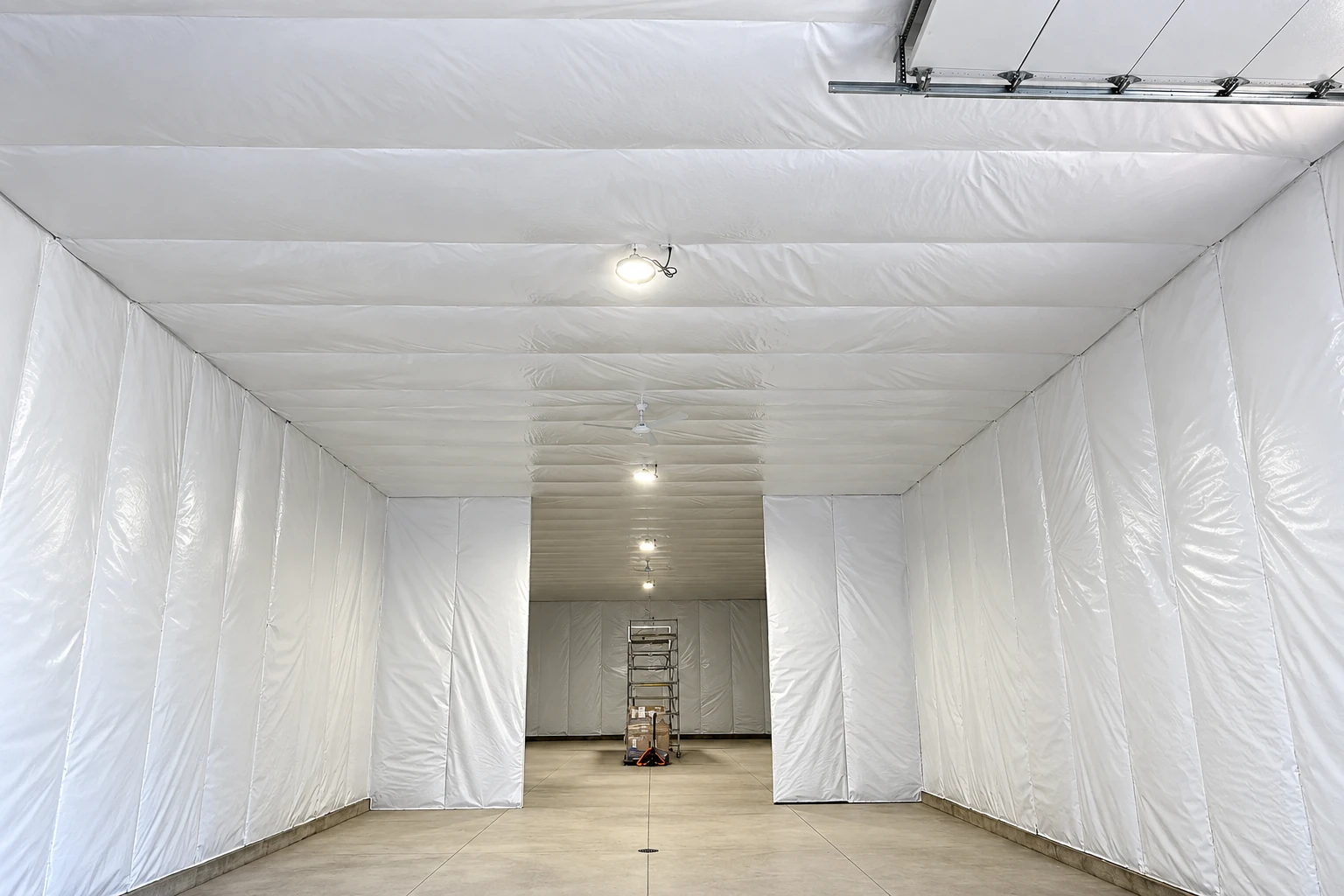 White insulation liner panels cover the walls and ceiling of a large commercial space, with a ladder at the far end.
